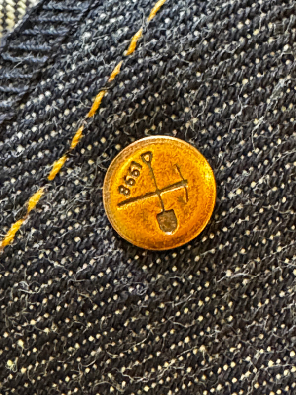 Gold coin with a design on a black denim background