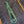 Embroidered design on a denim fabric with green thread and black needle.