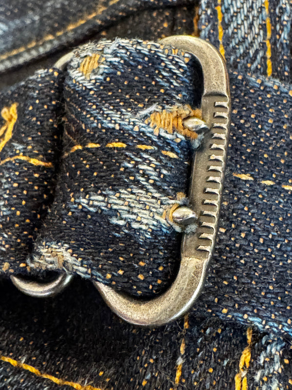 Close-up of a dark indigo denim belt with yellow contrast stitching and a silver-toned metal buckle.