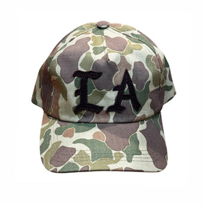 A baseball cap with a green, brown, and beige camouflage pattern, featuring black embroidered letters 'LA' on the front, set against a plain white background.
