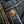 Close-up of a gold button on dark denim fabric with yellow stitching.