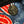 A close-up of a round metal button with a cross-shaped pin, set onto a blue denim fabric with red and white printed patterns.