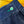 Close-up of a blue denim fabric with a green button on a wooden surface